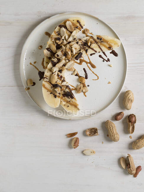 Halbierte Bananen mit Erdnüssen, Erdnussbutter und Schokolade — Stockfoto