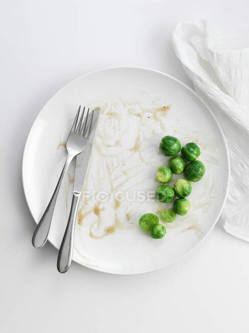 Брюссельская капуста на тарелке с остатками — стоковое фото
