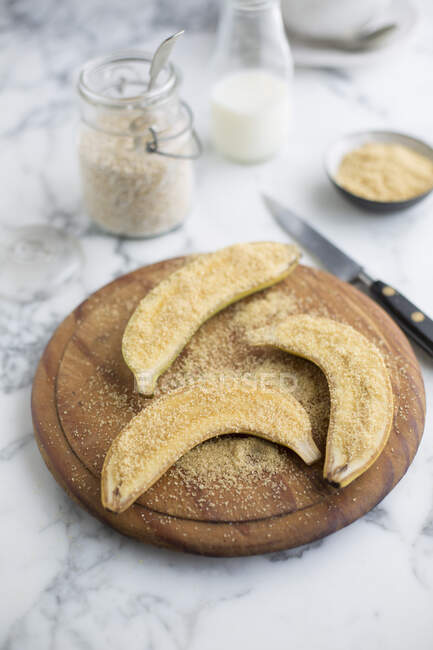 Bananas sprinkled with brown sugar on wooden plate — Stock Photo