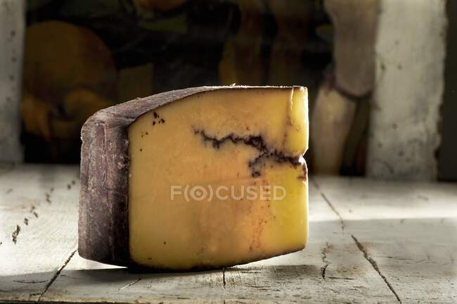 Cheese with a red wine rind on rustic wooden surface — Stock Photo