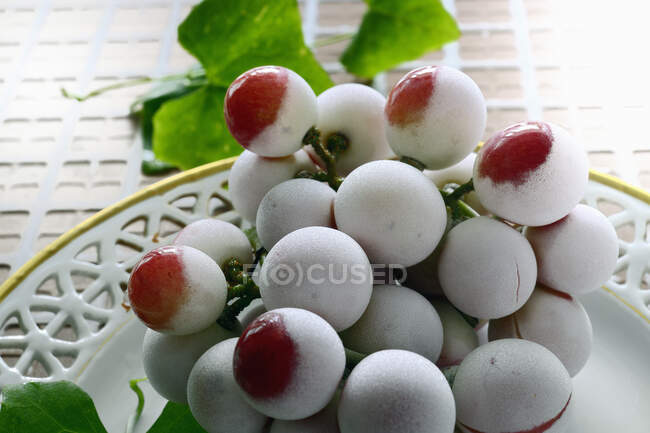 Uvas rojas congeladas en un plato - foto de stock