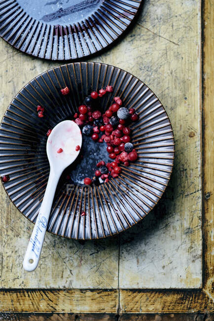 Remains of frozen berries in bowl with spoon — Stock Photo