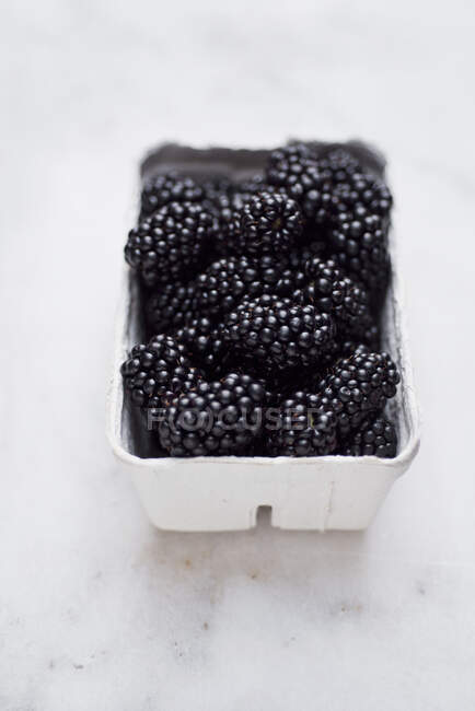 A punnet of fresh blackberries on a marble surface — Stock Photo