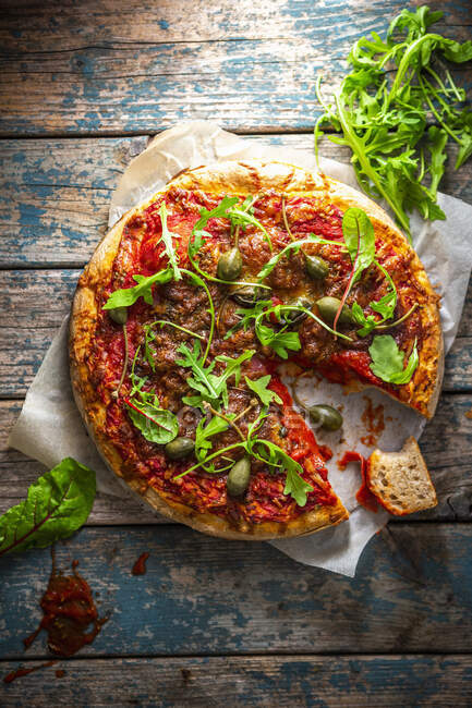 Dinkel-Pizza mit Salami, Rucola und Kapernäpfeln — Stockfoto