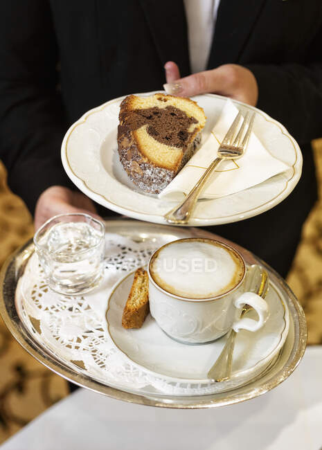 Garçonete serve café e um pedaço de bolo — Fotografia de Stock