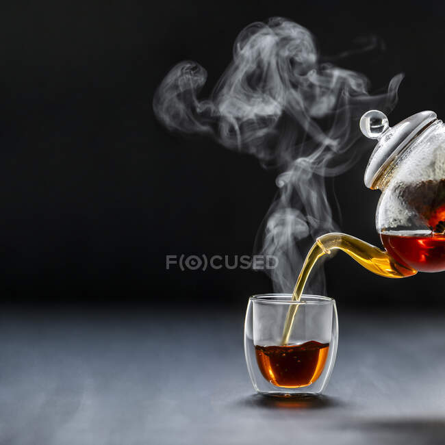 Pouring black tea, steaming — Stock Photo
