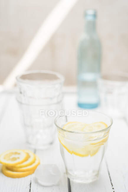 Água fresca em um copo com cubos de gelo e fatias de limão — Fotografia de Stock