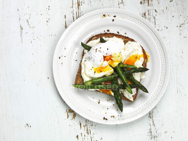 Poached eggs with green asparagus on toast - foto de stock