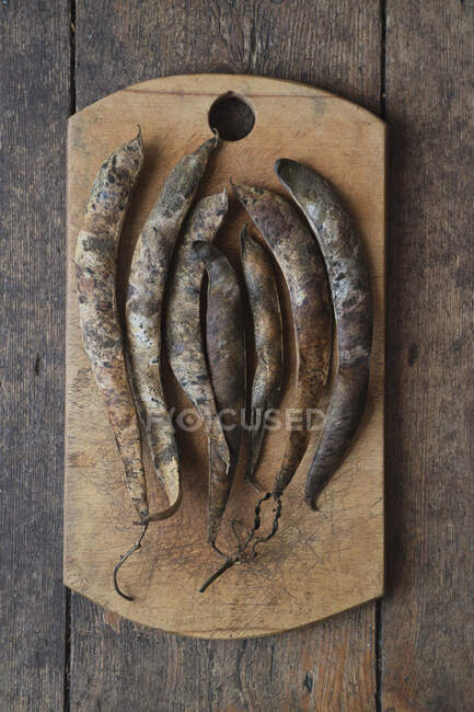 Dried bean pods on a rustic wooden board — Stock Photo