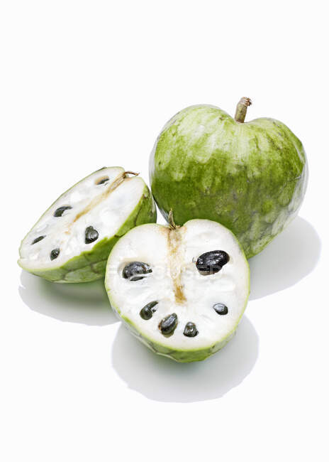 Cherimoya, whole and halved against a white background — Foto stock