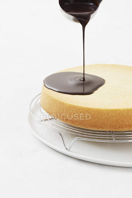 A cake being covered with a chocolate glaze — Stock Photo