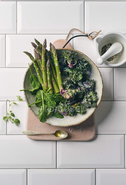 Mini asperges, pousses de fleurs et épinards dans un bol en céramique — Photo de stock