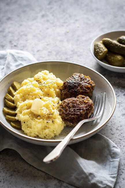 Burgers with mashed potatoes and pickles with fork on plate — Stock Photo