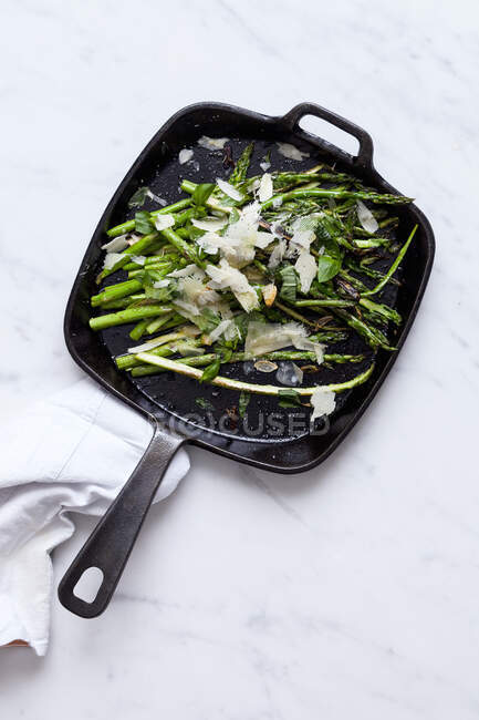 Green asparagus with parmesan in a pan — Stock Photo