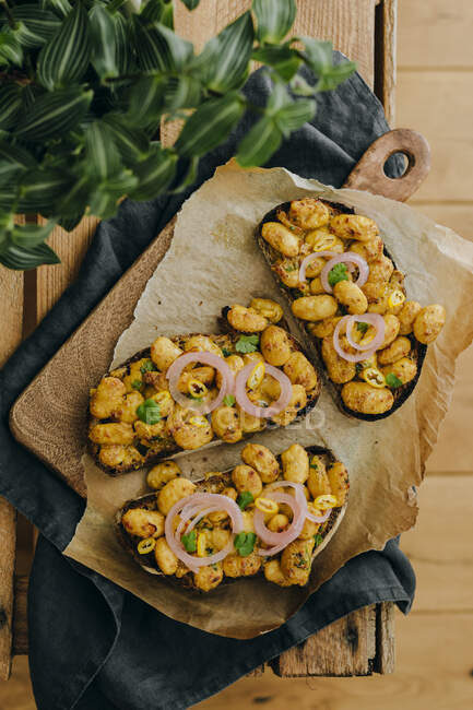 Grilled bread topped with curried beans and onions — Stock Photo
