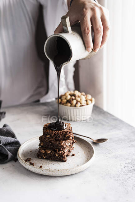 Pouring chocolate sauce on brownies — Stock Photo