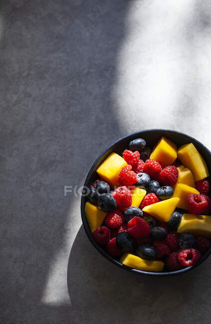 Salade de fruits colorés avec morceaux de mangue, framboises et bleuets — Photo de stock