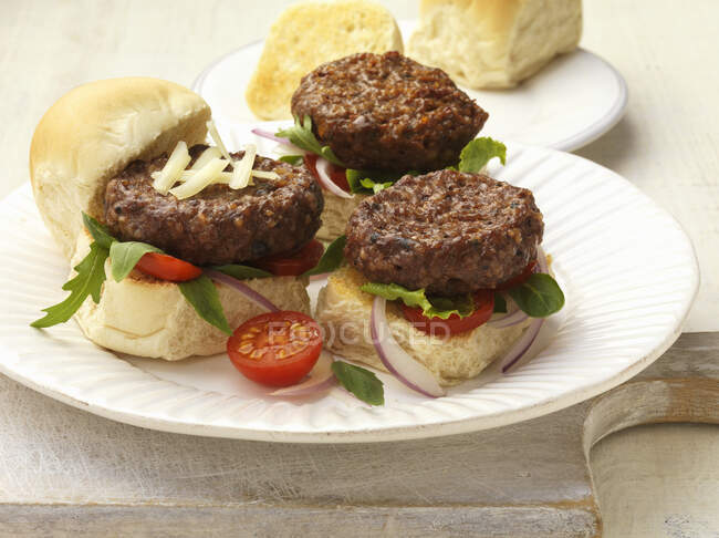 Mini burgers with a tomatoes and rocket on a plate — Stock Photo