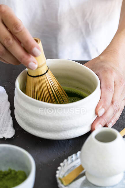 Whipping matcha tea with a bamboo whisk — Stock Photo