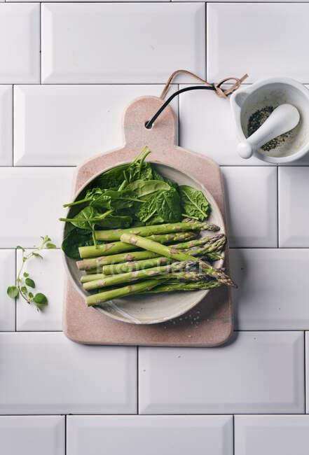 Зелена мініатюрна спаржа і свіжий шпинат у керамічній посудині. — стокове фото