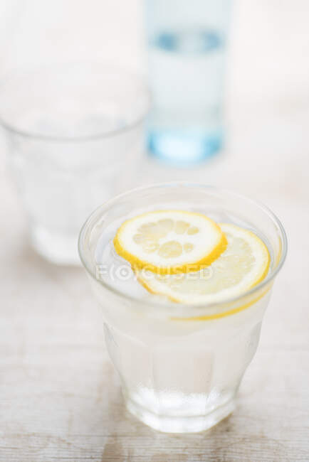 Свежая вода в стакане со льдом и ломтиками лимона — стоковое фото