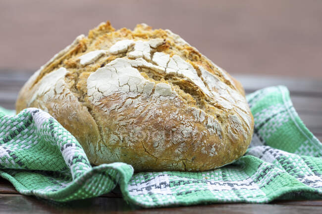 A loaf of wheat bread on a tea towel — Stock Photo