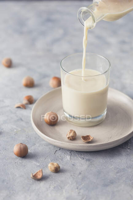 Versare il latte di nocciola in un bicchiere — Foto stock
