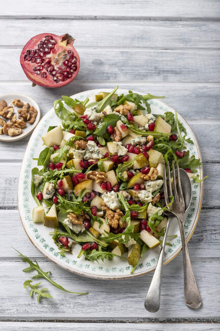 Birne, Salat mit Gorgonzolakäse, Pomagranatkernen, Rucola, Walnüssen, Walnüssen und der Hälfte Granatapfel — Stockfoto