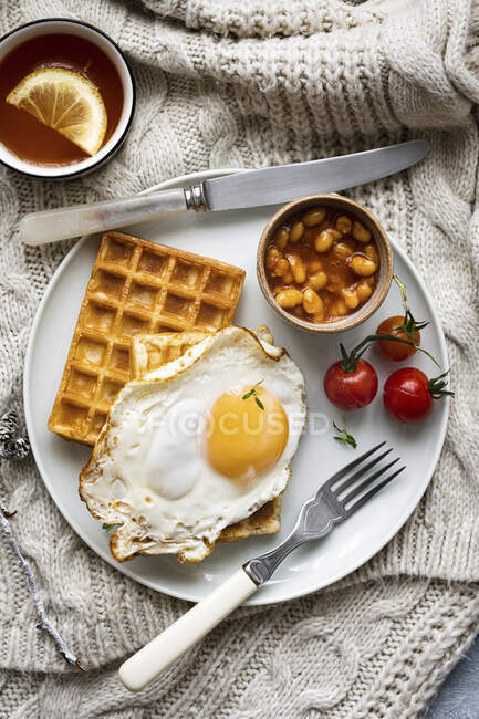 Breakfast with fried egg, baked beans and waffles — Stock Photo