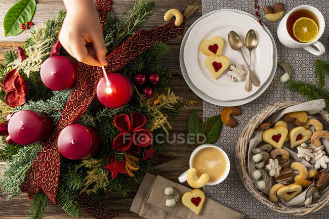 Ein beleuchteter Adventskranz neben einem Teller mit Keksen, Kaffee und Tee — Stockfoto