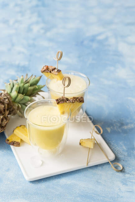 Alcohol cocktails with fresh pineapple juice and slices with sticks in glasses — Stock Photo