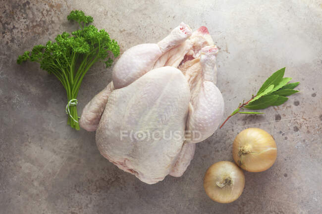 Ingredientes para caldo de galinha: um frango cru inteiro, ervas e cebolas — Fotografia de Stock