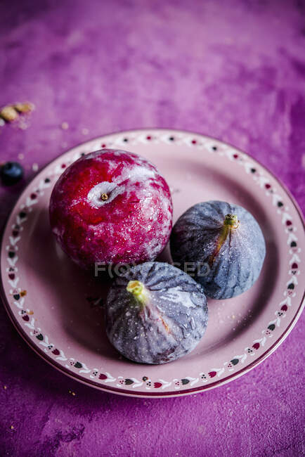 Prune et figues sur plaque céramique rose — Photo de stock