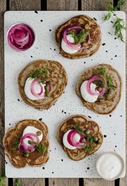 Blinis with sour cream and pickled onions — Stock Photo