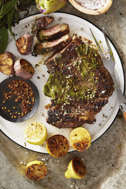 Grilled steak with garlic and lemons — Stock Photo