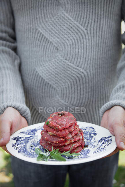 L'homme tient des galettes de hamburger pour barbecue — Photo de stock