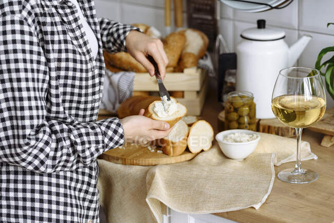 Frau in der Küche macht Sandwiches aus Baguette und Frischkäse — Stockfoto