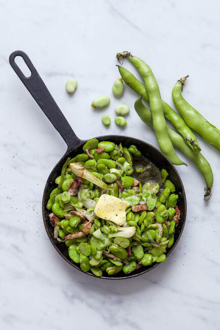Fried broad beans with bacon in a pan — Stock Photo