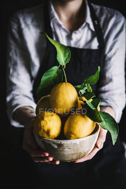Donna che tiene ciotola con limoni — Foto stock