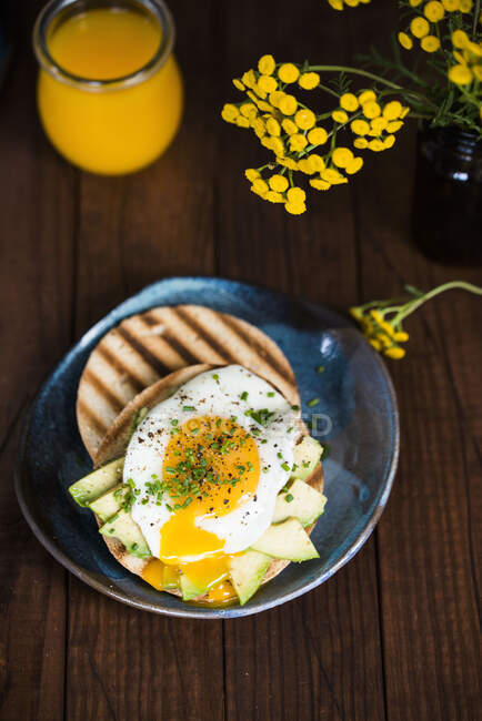 Bagel with avocado slices and fried egg — Stock Photo