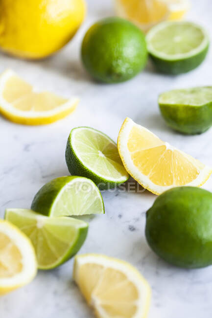 Limones y limas enteros, cortados a la mitad y rebanadas - foto de stock