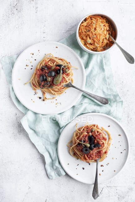Spaghetti Puttanesca serviert mit Karottensalat — Stockfoto