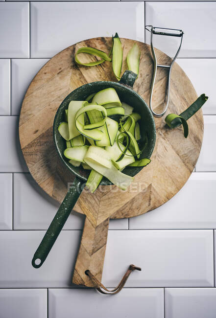 Fresh green vegetables on wooden cutting board with knife and fork on kitchen table — Stock Photo