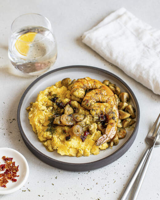 Polenta with mushrooms and shrimps and glass of water — Stock Photo