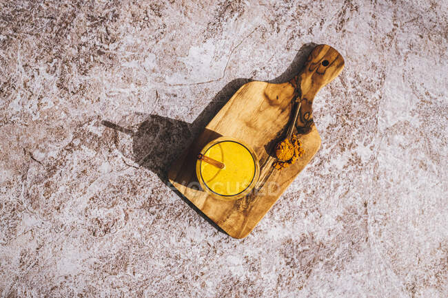 Leche dorada en vidrio con paja de vidrio y cúrcuma molida - foto de stock