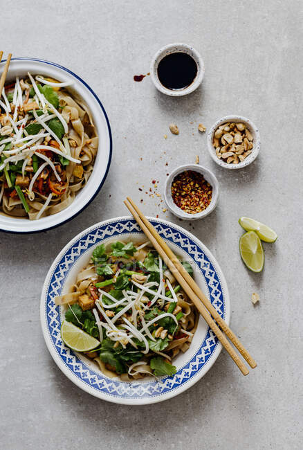 Stir-fried noodles with vegetables and chopsticks on black background — Stock Photo