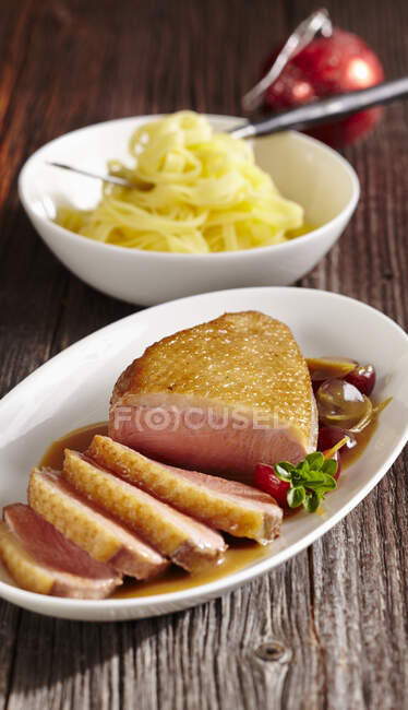 Poitrine de canard rôtie avec sauce au raisin et tagliatelles — Photo de stock
