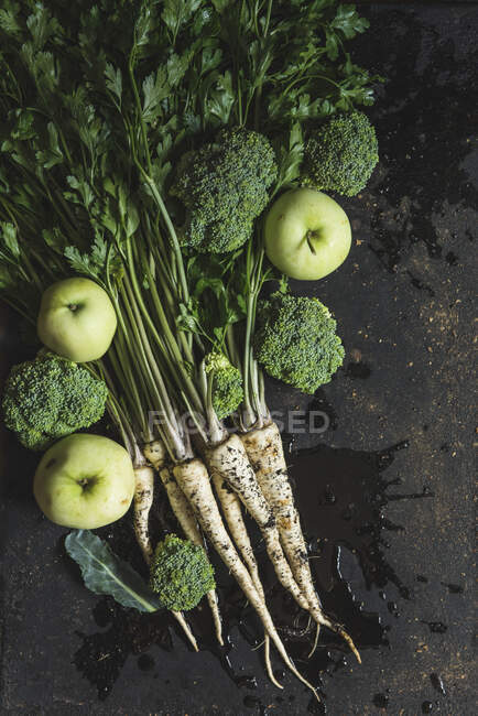 A bunch of parsley, broccoli florets and green apples on dark background — Stock Photo