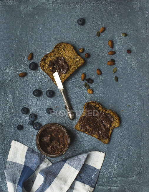 Wholegrain bread toasts with organic vegan chocolate peanut butter, blueberries and nuts — Stock Photo