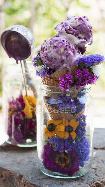 Fruits of the forest ice cream in a cone served with summer flowers in a jar — Stock Photo